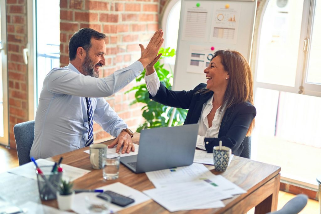 Succesvol advies. Man en vrouw geven elkaar een highfive.